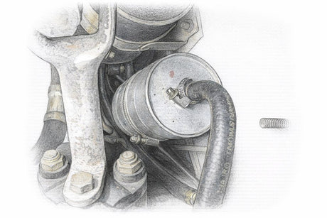 BMW E36 fuel filter mounted under the car with its worm-gear hose clamp and fuel line attached.