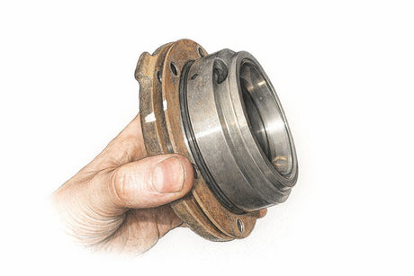 BMW E30 differential drive flange and output shaft seal held in hand, the parts renewed in this repair.